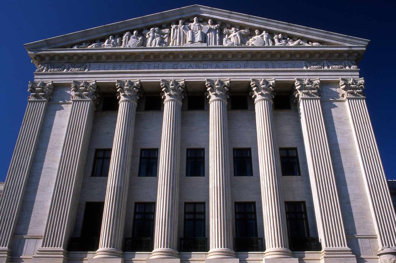 Federal courthouse exterior with columns inscribed Justice the Guardian of Liberty